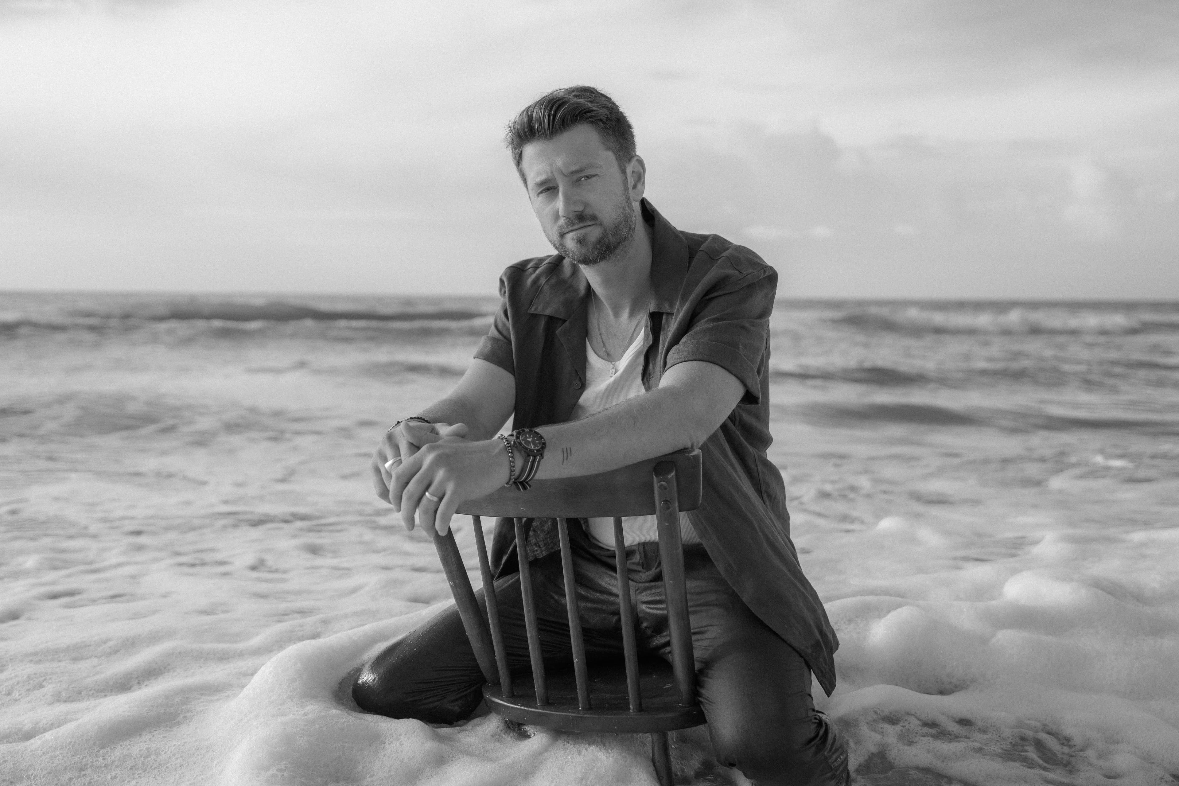 Adam Doleac seated on a wooden chair in the ocean for the 3 Minute Summer campaign